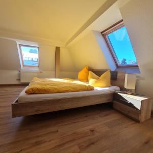 艾本施托克Wurzelrudis Hostel的一间卧室配有一张带黄床单的床和两个窗户。
