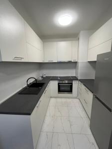萨格勒布Apartman Anton的厨房配有白色橱柜和黑色台面