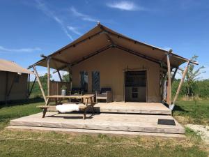 KekerdomDe Hazelaarshof Luxe glampingtent bij natuurgebied De Millingerwaard的帐篷配有桌子和木甲板