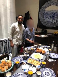 非斯Dar Chez Khadija的男人和女人站在餐桌旁,一边吃着食物