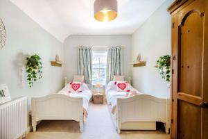 斯沃尼奇Passiflora Cottage的带窗户的客房内设有两张单人床。