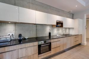 安锡Le Kube - Appartements de Prestige au centre d'Annecy的厨房配有白色橱柜和黑色台面