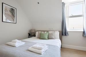 亨顿The Finchley Apartment的白色卧室配有带2条毛巾的床