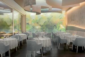 加尔尼亚诺加尔达湖乐法逸酒店度假酒店及Spa的一间设有白色桌椅的餐厅,