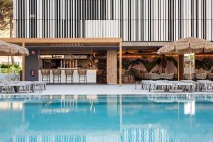 贝尼多姆Hotel Primavera Park的大楼内带桌子和遮阳伞的游泳池