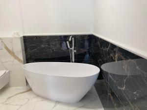 莫斯蒂Apartament BŁĘKITNA MEWA的浴室铺有黑色瓷砖,配有白色浴缸。