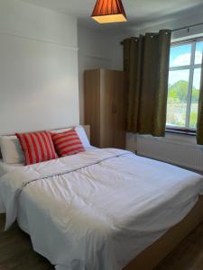 Morden3 bedroom house in Sutton的卧室内的白色床和红色枕头