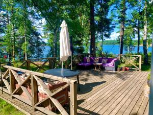 斯德哥尔摩Charmig stuga av rustik stil i Stockholms område的一个带遮阳伞和紫色椅子的木制甲板