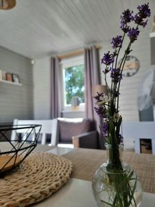 帕克Domki z jacuzzi nad zatoką的花瓶,花朵紫色,坐在桌子上