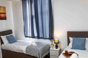 莱斯特Silver Apartment 2 Bed Flat Leicester City Centre的一间卧室设有两张床,窗户配有蓝色窗帘