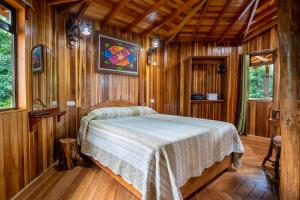 蒙泰韦尔德哥斯达黎加Casitas del Bosque Monteverde.的木制客房内的一间卧室,配有一张床