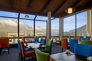 皇后镇国敦酒店的餐厅配有桌椅,位于山脉的背景中