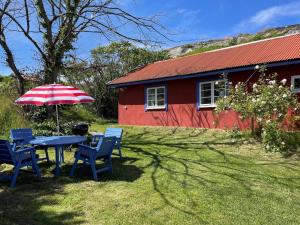 谢尔港Holiday home Skärhamn VII的红色房子前的桌椅和雨伞