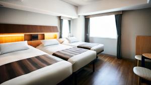 东京Hotel Monte Hermana Tokyo的酒店客房设有两张床和窗户。