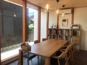 直岛町Quaint House Naoshima的一间带木桌和书架的用餐室