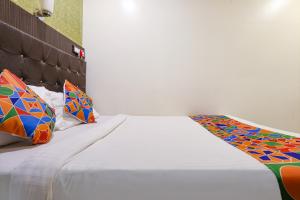 孟买Hotel Aksa Powai的一张白色的床,上面有色彩缤纷的枕头