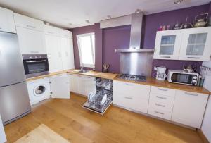 塔里法Apartamento con terraza的厨房配有白色橱柜和紫色墙壁