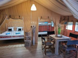 Saint-Martin-des-BesacesTente Lodge Safari的配有桌椅和床的帐篷