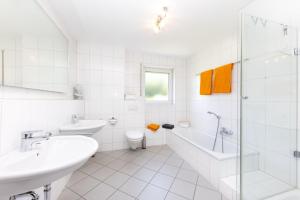 锡根Sonnendeck4的白色的浴室设有浴缸、水槽和卫生间。