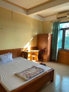 Móng CáiNhà nghỉ FAMY的一间卧室配有一张床、一张书桌和一个窗户。