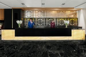 卡拉奇卡拉奇莫凡彼酒店的大厅设有黑色和黄色的墙壁,有三人