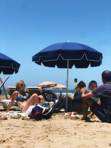 塔姆拉赫特乌兹达尔Manzili Surfhouse的一群人坐在海滩上,在伞下