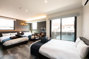 鹿儿岛T・Kスクエア鹿児島中央的酒店客房设有三张床和阳台