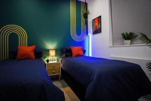 斯蒂夫尼奇Luxury Stevenage Town Centre Apartment的配有两张床铺的蓝色和绿色墙壁客房