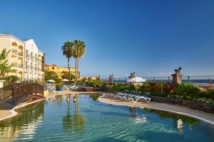 丰沙尔Hotel Porto Santa Maria - PortoBay - Adults Only的棕榈树度假村的游泳池