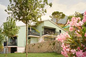 ViganelloReka-Feriendorf Albonago的一座带石墙和粉红色花卉的绿色房子