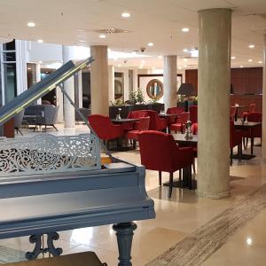 美因河畔法兰克福Hotel Schopenhauer Hof的大堂设有餐厅,配有红色椅子和钢琴
