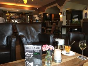 Hoogezand法贝尔酒店的酒吧配有黑色皮椅和带酒杯的桌子