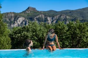 拉博姆Charmant camping Familiale 3 Etoiles vue 360 plage piscine à débordement empl XXL的两个女孩坐在游泳池里