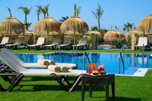 雷塔马尔Cabogata Beach Hotel的一个带游泳池、椅子和桌子的度假村