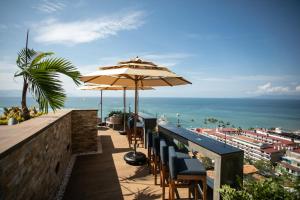巴亚尔塔港Pinnacle Resorts 179 - Adults Only的一间酒吧,配有椅子和遮阳伞,俯瞰着大海