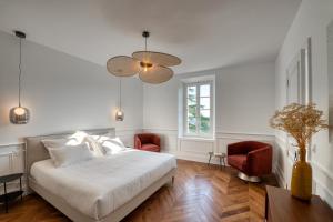Le BarrouxL'Iris de Suse的一间卧室配有白色的床和两张红色椅子