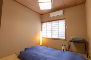佐渡市guesthouse UZU Sado - Vacation STAY 90684v的一间卧室设有蓝色的床和窗户。