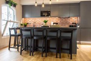 普里茅斯Plymouth Barbican boutique luxury Apartment的厨房配有带黑色凳子的黑色吧台