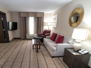 夏洛特夏洛特机场假日酒店的酒店客房设有一间带沙发和椅子的客厅
