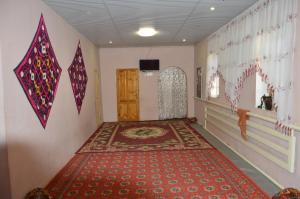 希瓦Khiva Mirza Bobur Guest House的一间铺有红地毯的客房,墙上放风筝