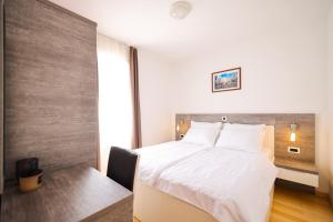 佩特坎内Dok Apartment的卧室配有白色的床、书桌和窗户。