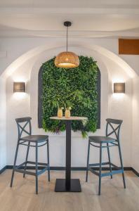 罗列特海岸Hotel Lloret Santa Rosa by Pierre & Vacances的一张桌子、三把椅子和绿色的墙壁