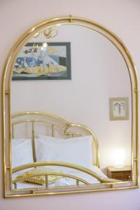 佩塔里德海昂Gold n Blu Petalidi的床上方的金色镜子,带白色枕头