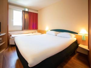 弗里堡弗里堡宜必思酒店的酒店客房设有一张白色大床和一个窗户。