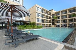 莱卡邦素万那普BS住宿酒店 - SHA Extra Plus的一座带椅子和遮阳伞的游泳池位于一座建筑旁边