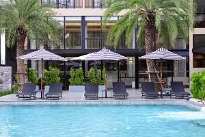 莱卡邦素万那普BS住宿酒店 - SHA Extra Plus的一个带椅子和遮阳伞的游泳池以及棕榈树