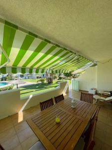 埃尔波提尔Casa adosada con porche, piscina y pista de pádel, junto al campo de golf的用餐室配有木桌和绿色及白色遮阳篷