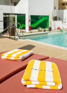 福恩吉罗拉Caleyro Boutique Apartments - "Parking incluido"的游泳池旁的桌子上摆放着两条毛巾