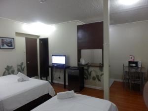 奥隆阿波Casa Saudade Condotels and Transient Rooms的酒店客房设有两张床和电视。