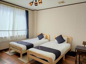 柏崎市Tabist Business Hotel Chitose Kashiwazaki的带窗户的客房内的两张床